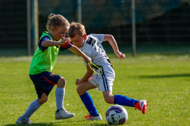 Una nena y un nene disputan una pelota en un partido de fútbol infantil