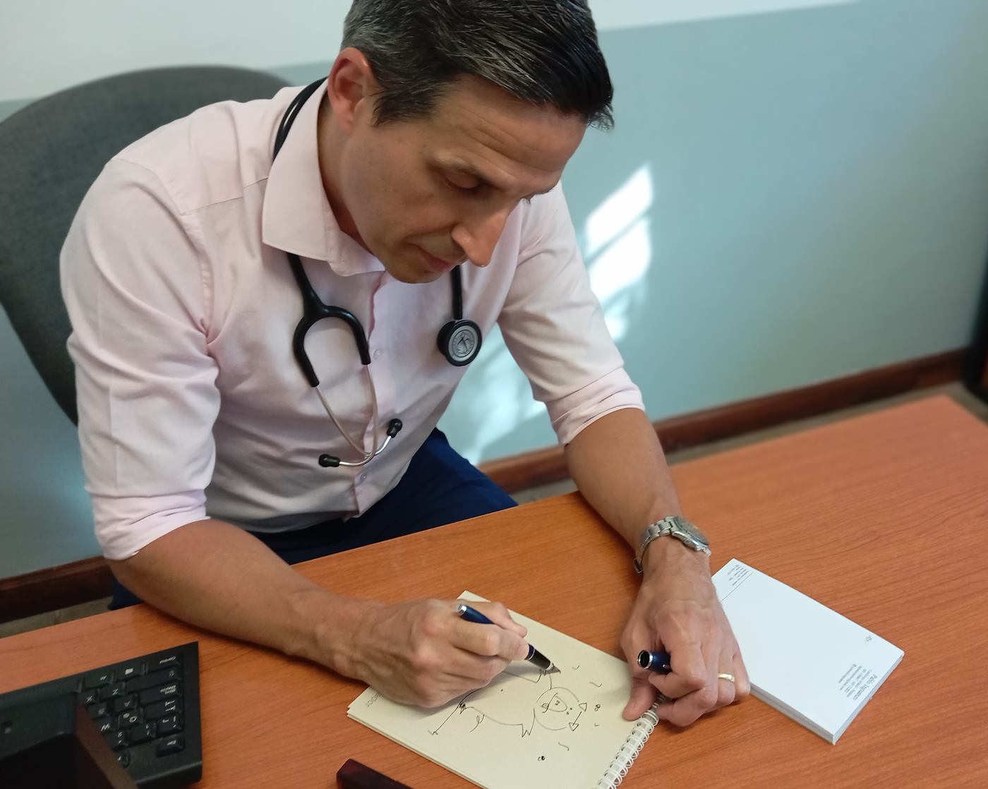 Dr. Pablo Inguanzo dibujando en su escritorio, con el estetoscopio colgado