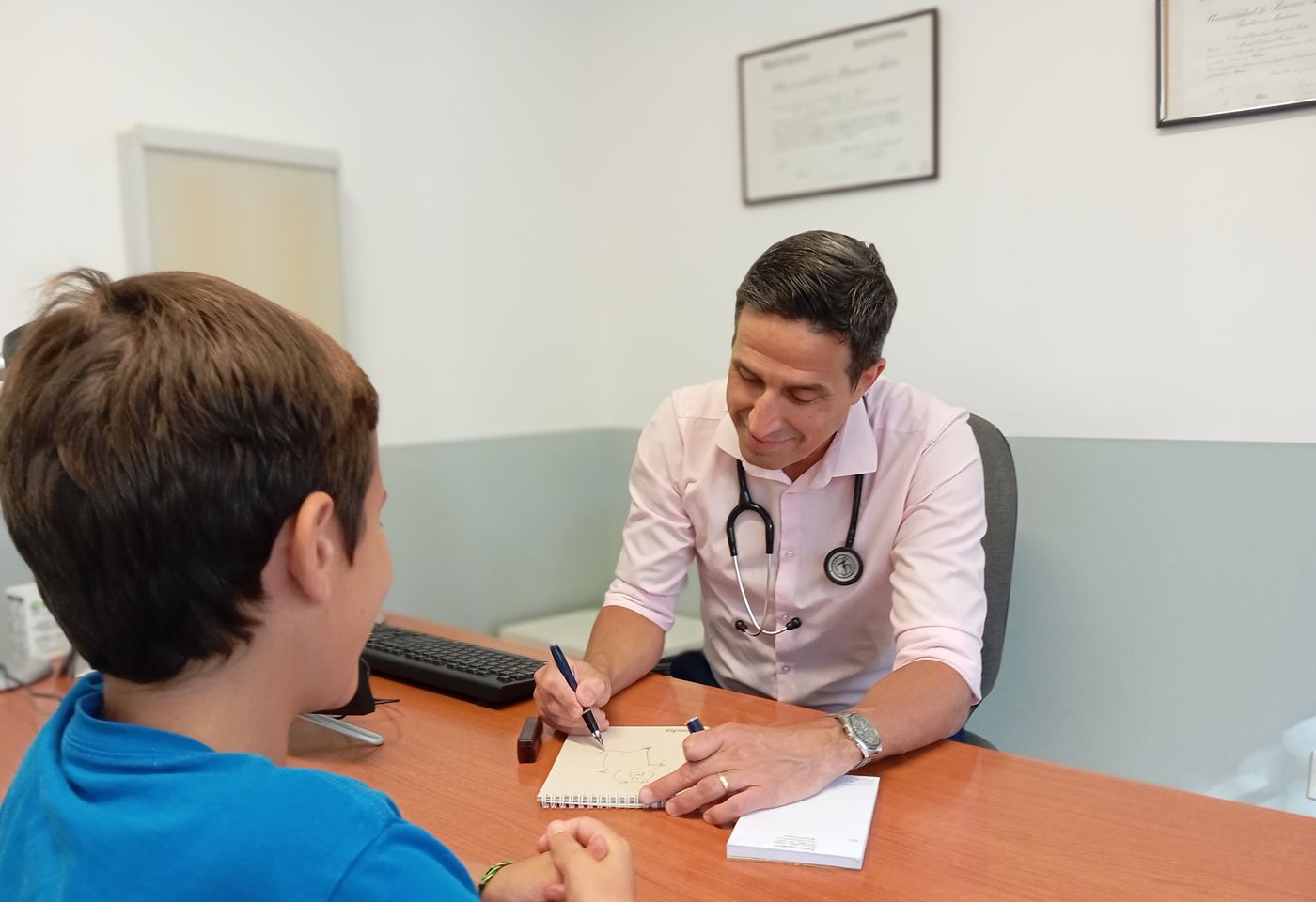 Dr. Pablo Inguanzo conversa con un chico y le dibuja algo durante la consulta